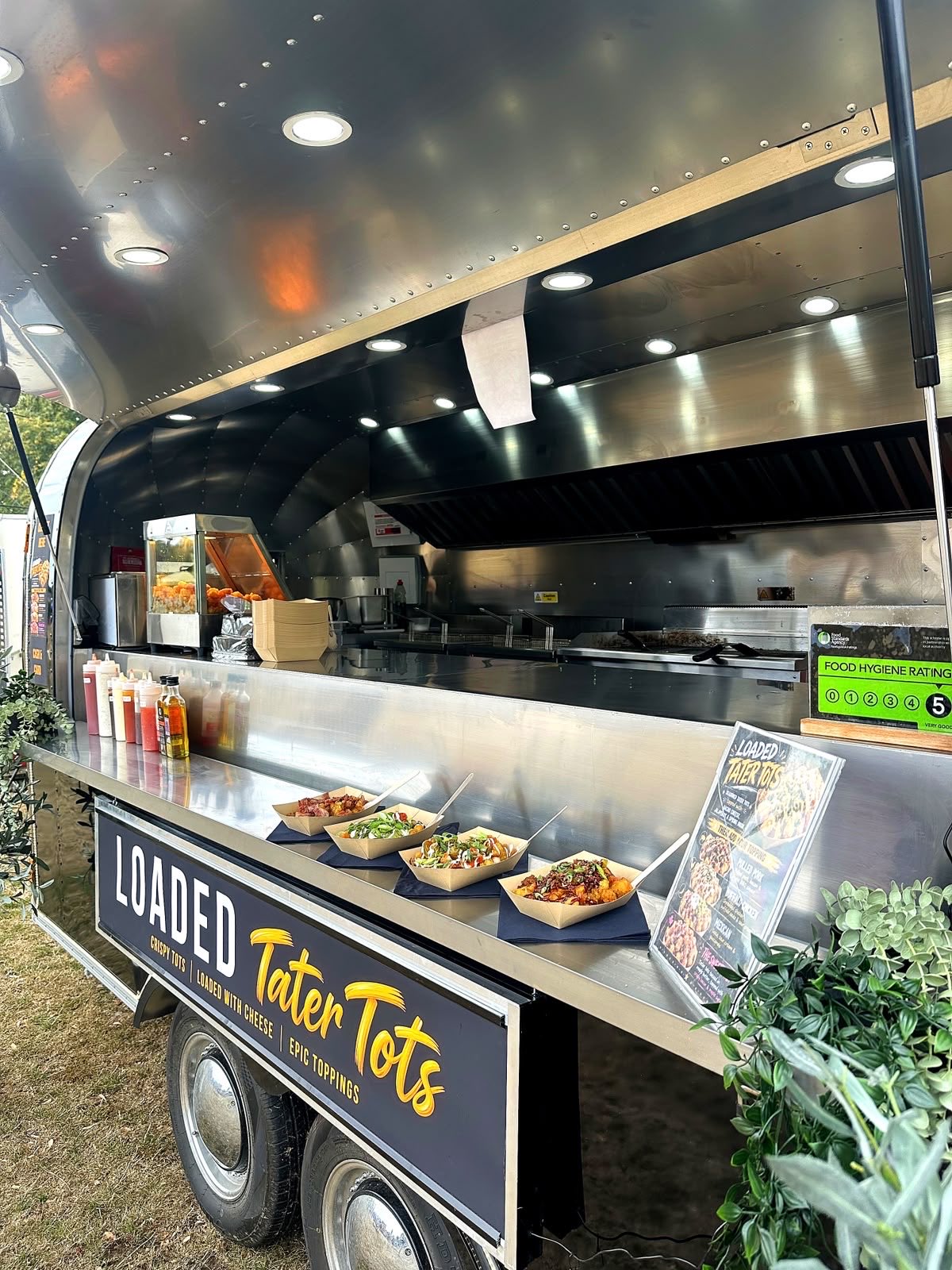 Inside the Airstream kitchen's hatch - loaded trays ready to serve, sauces lined up and the 5-star hygiene rating on display.