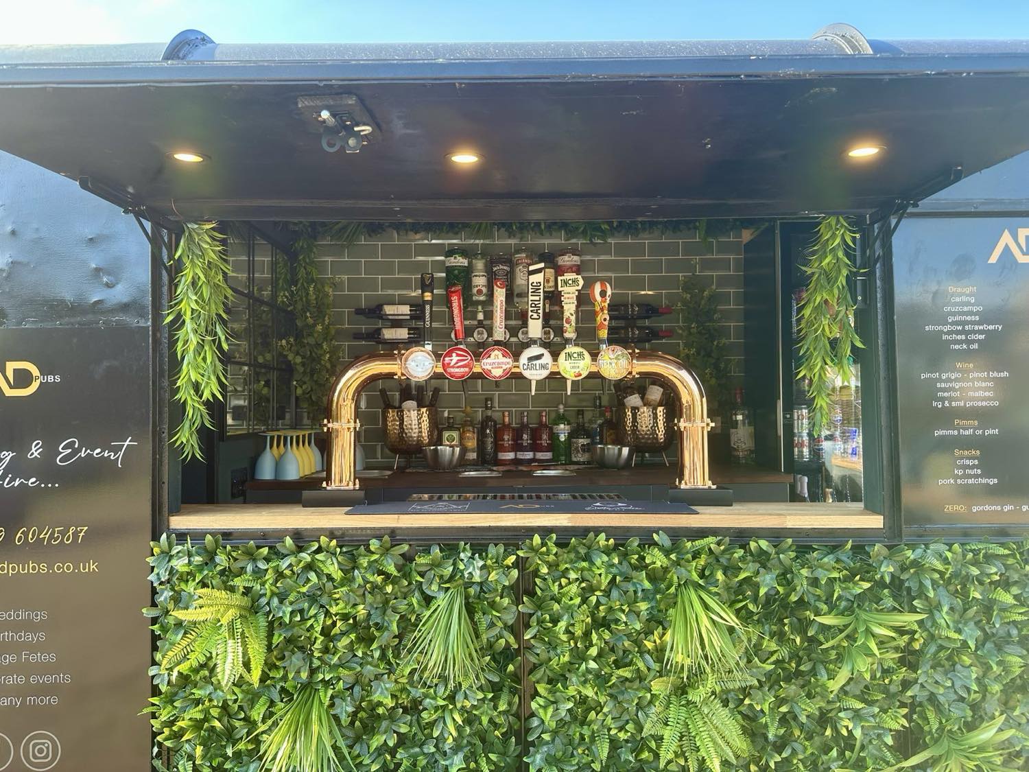 The ADevents horsebox bar front-on, copper taps gleaming, dressed with foliage.