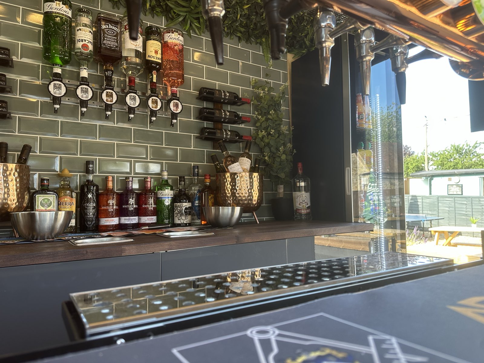 Optics and premium spirits along the tiled back bar inside the horsebox.