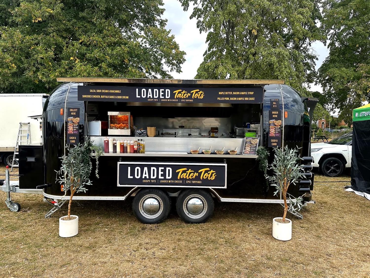 A pop-up Aperol spritz bar with a flower wall, set against open countryside at golden hour.